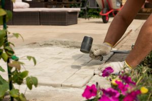 The master lays paving stones in layers. Garden brick pathway paving by professional paver worker.